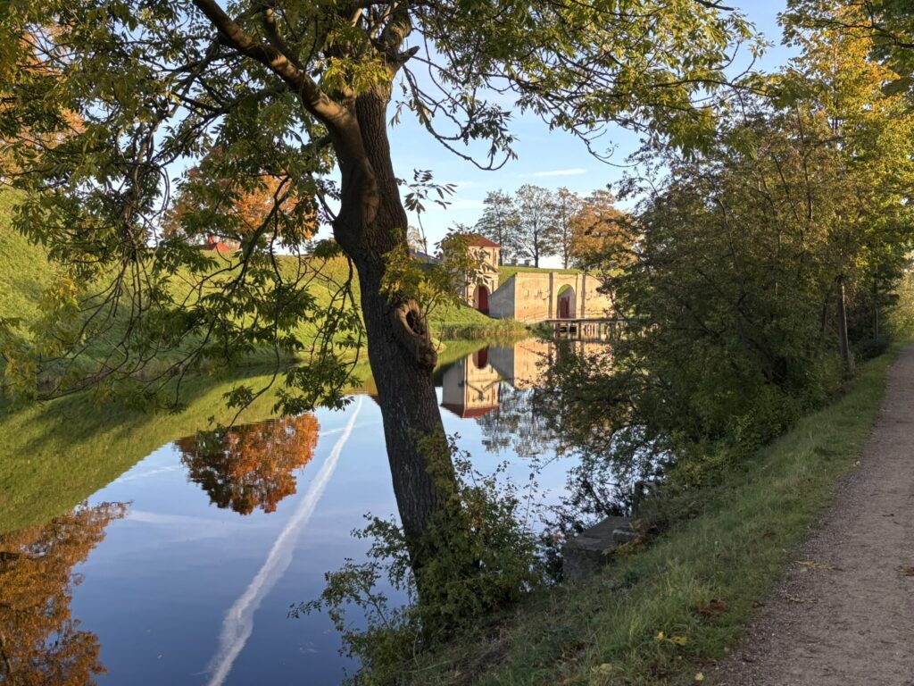 Indgangen til Kastellet set gennem træerne med voldgraven i forgrunden.