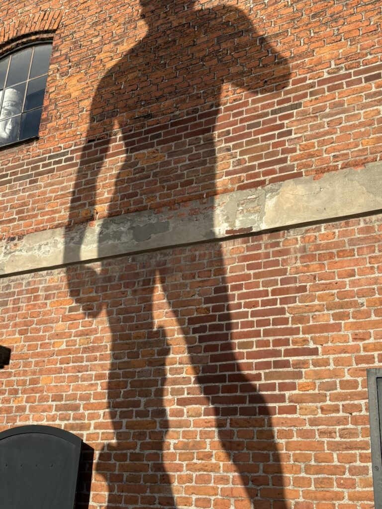Skygge fra lavt sollys på en gammel murstensfacade.